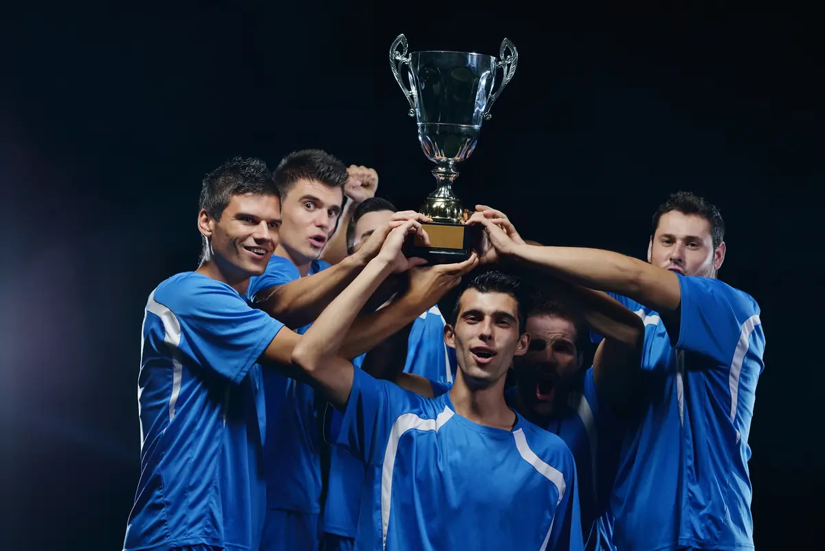 Time de futebol erguendo a taça de campeão
